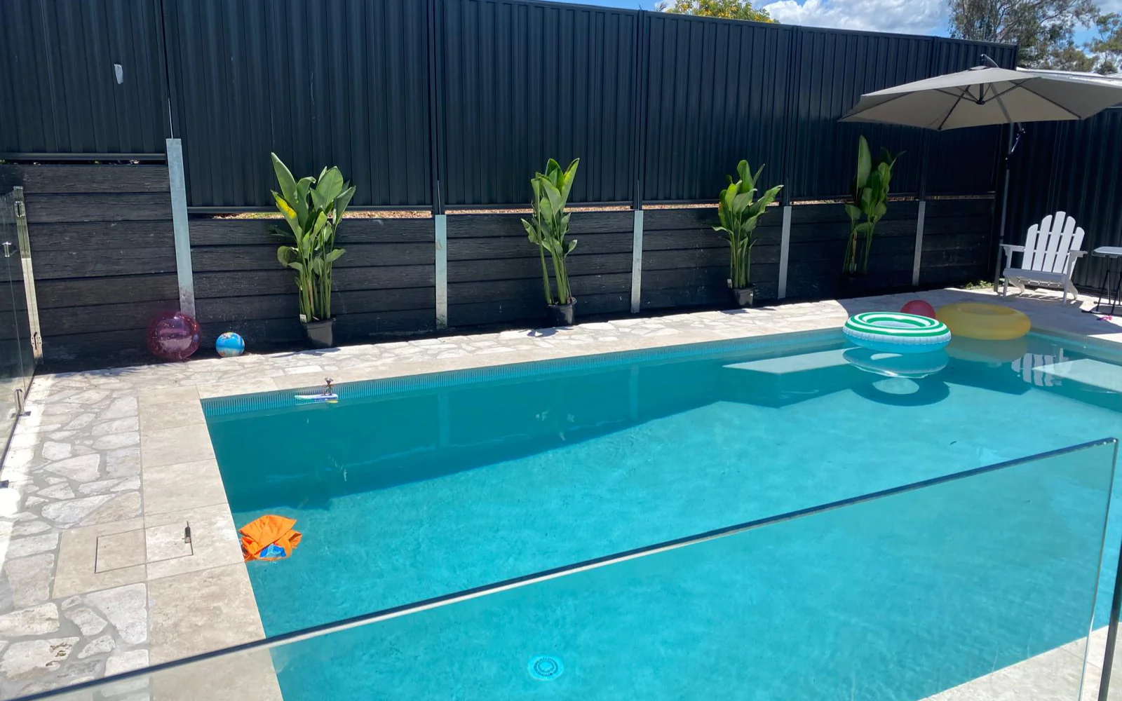 Finished LuxRo pool with travertine surrounds, planting and umbrella